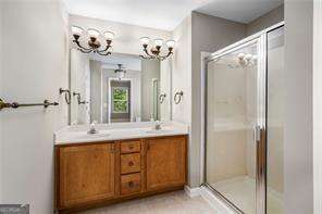 bathroom with a shower with door, vanity, and a chandelier