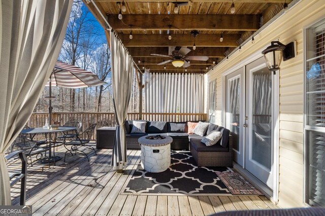 wooden terrace featuring ceiling fan and an outdoor living space with a fire pit