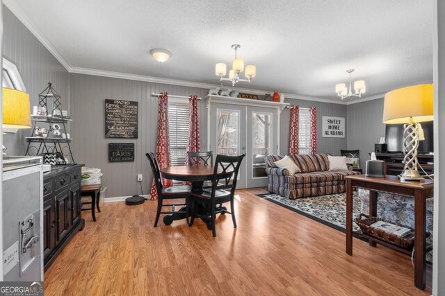 dining space featuring a textured ceiling, a notable chandelier, light wood-type flooring, and crown molding