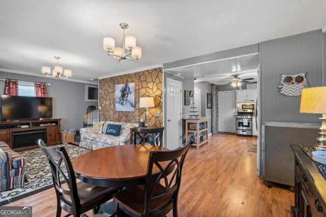 dining area with ceiling fan with notable chandelier, light hardwood / wood-style floors, ornamental molding, and a textured ceiling