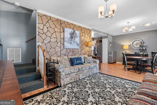 living room featuring crown molding, hardwood / wood-style floors, a chandelier, and a textured ceiling