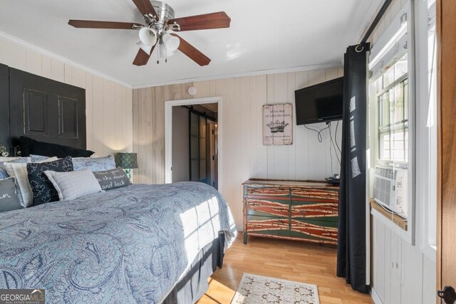 bedroom featuring ceiling fan, light hardwood / wood-style floors, crown molding, and cooling unit