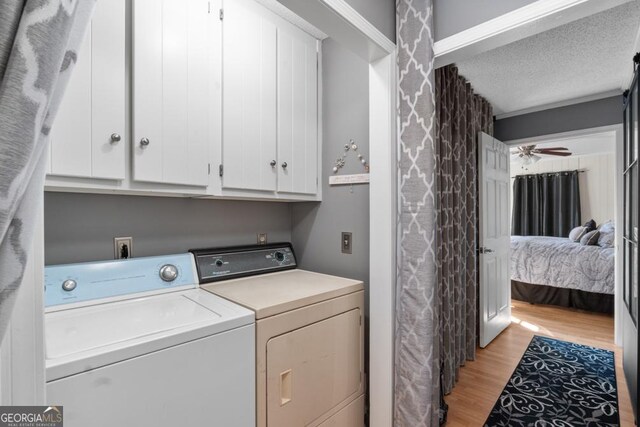 clothes washing area with cabinets, washer and dryer, ceiling fan, light wood-type flooring, and a textured ceiling