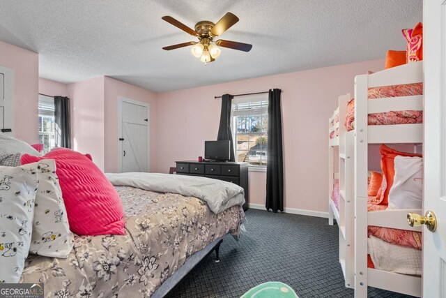 bedroom featuring ceiling fan, dark carpet, a textured ceiling, and multiple windows