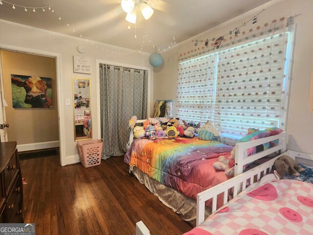 bedroom featuring dark hardwood / wood-style flooring, ceiling fan, and ornamental molding