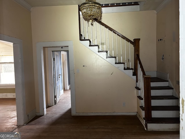 stairway with hardwood / wood-style flooring, ornamental molding, and an inviting chandelier