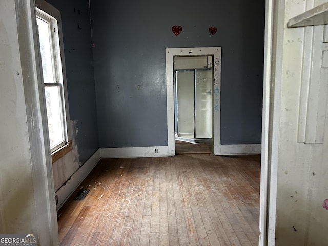 unfurnished room featuring plenty of natural light and wood-type flooring