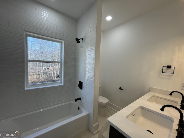 full bathroom featuring vanity, tiled shower / bath, and toilet