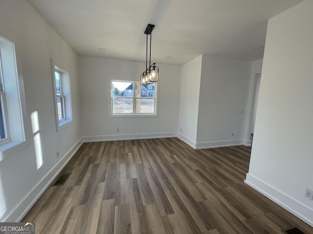 unfurnished dining area featuring dark hardwood / wood-style flooring and a notable chandelier