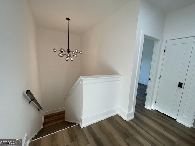 stairs featuring wood-type flooring and a notable chandelier