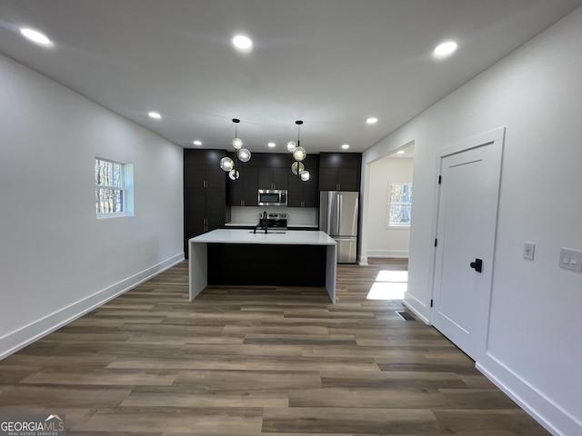 kitchen featuring pendant lighting, sink, dark hardwood / wood-style flooring, a kitchen island with sink, and stainless steel appliances