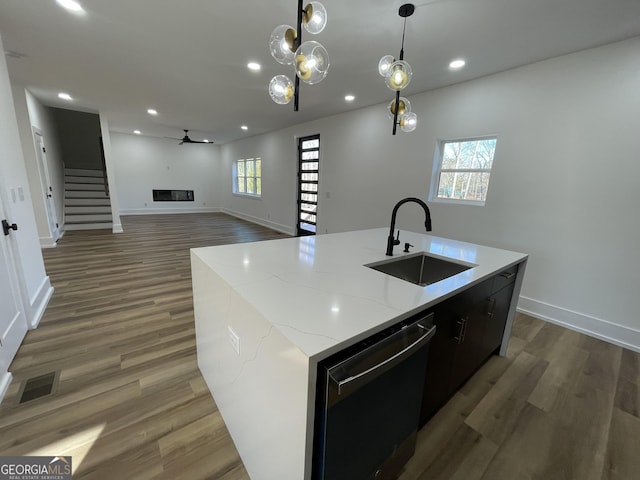 kitchen with dishwasher, sink, a center island with sink, and decorative light fixtures