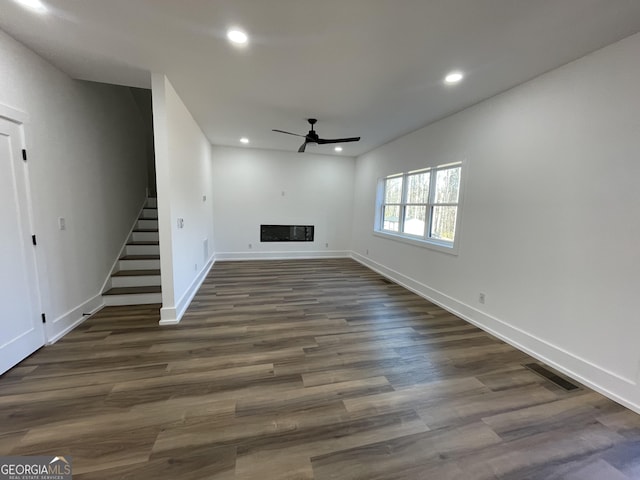 unfurnished living room featuring ceiling fan and dark hardwood / wood-style flooring