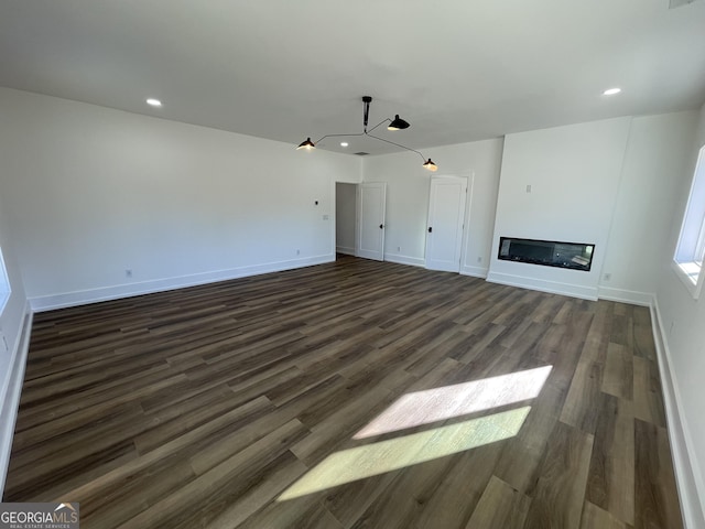 unfurnished living room with an inviting chandelier and dark hardwood / wood-style floors