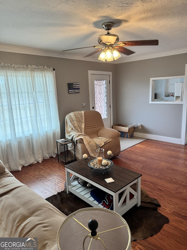 living room featuring ceiling fan, wood-type flooring, a textured ceiling, and ornamental molding