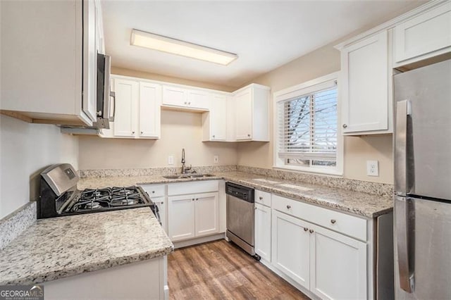 kitchen featuring white cabinets, appliances with stainless steel finishes, hardwood / wood-style flooring, and sink