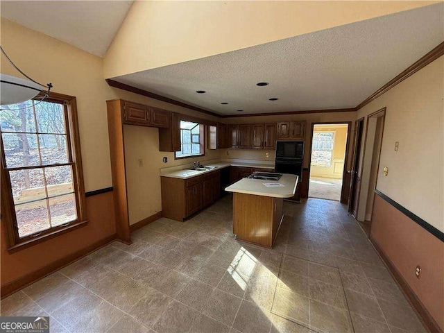 kitchen featuring sink, a textured ceiling, a kitchen island, black appliances, and ornamental molding