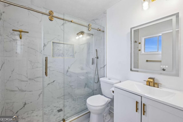 bathroom featuring vanity, a shower with shower door, and toilet