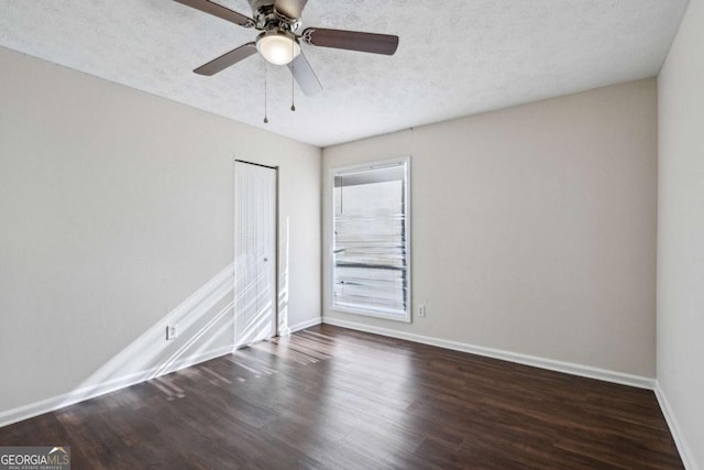 empty room with ceiling fan, a textured ceiling, and dark wood-type flooring