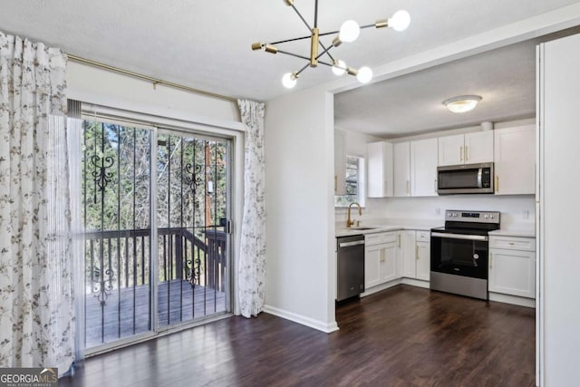 kitchen featuring sink, dark wood-type flooring, stainless steel appliances, decorative light fixtures, and white cabinets