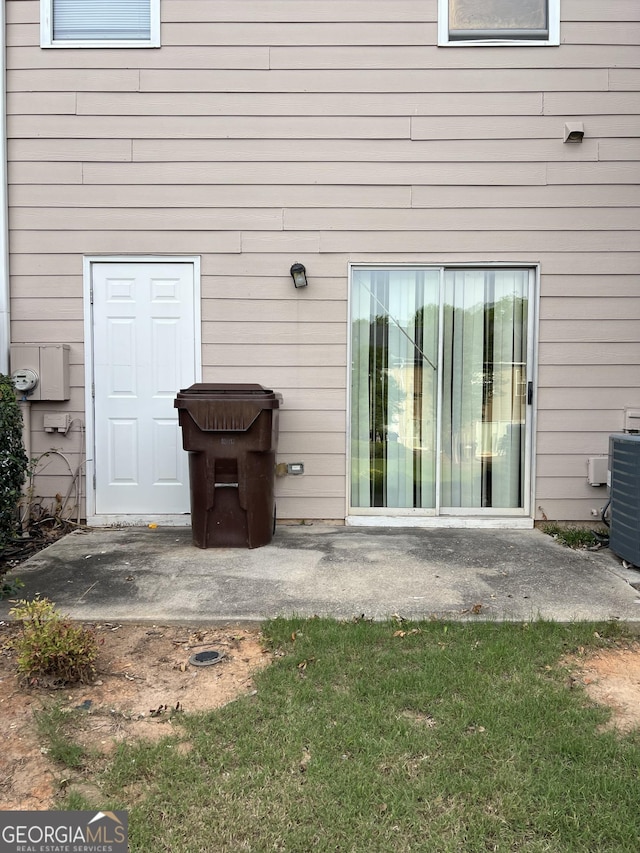 property entrance with central AC, a patio area, and a yard