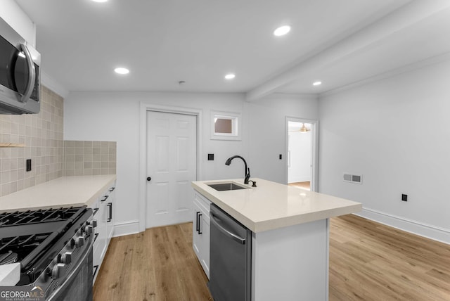 kitchen with backsplash, white cabinets, a center island with sink, sink, and stainless steel appliances