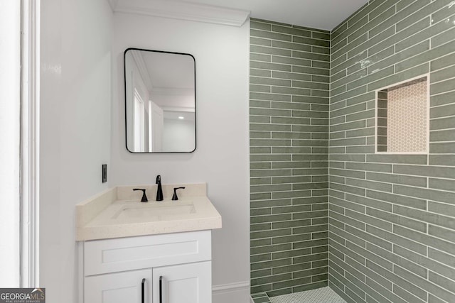 bathroom with tiled shower, vanity, and ornamental molding