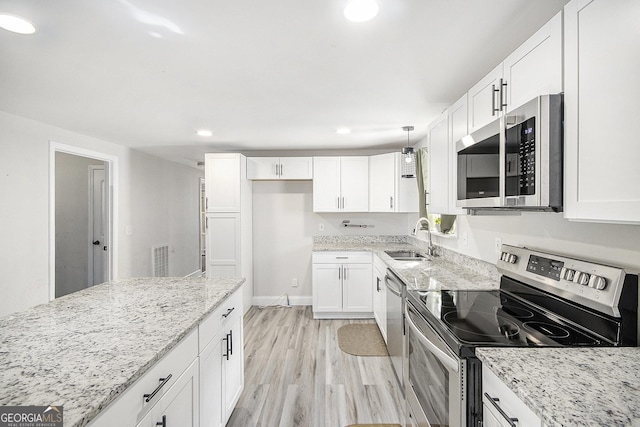 kitchen with white cabinetry, sink, light stone countertops, hanging light fixtures, and stainless steel appliances