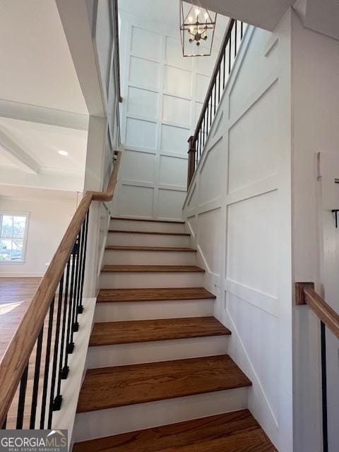 staircase with wood-type flooring and a chandelier