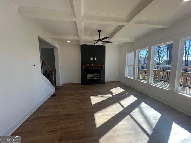 unfurnished living room with ceiling fan, beam ceiling, dark hardwood / wood-style flooring, and coffered ceiling