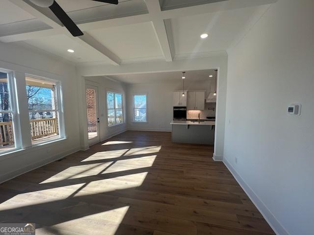 unfurnished living room with beamed ceiling, dark hardwood / wood-style flooring, ceiling fan, and coffered ceiling