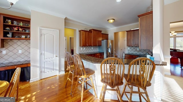 kitchen featuring stainless steel refrigerator with ice dispenser, ornamental molding, decorative backsplash, and light wood-type flooring