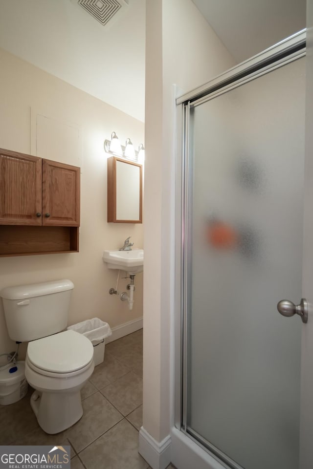 bathroom featuring a shower with shower door, tile patterned floors, and toilet