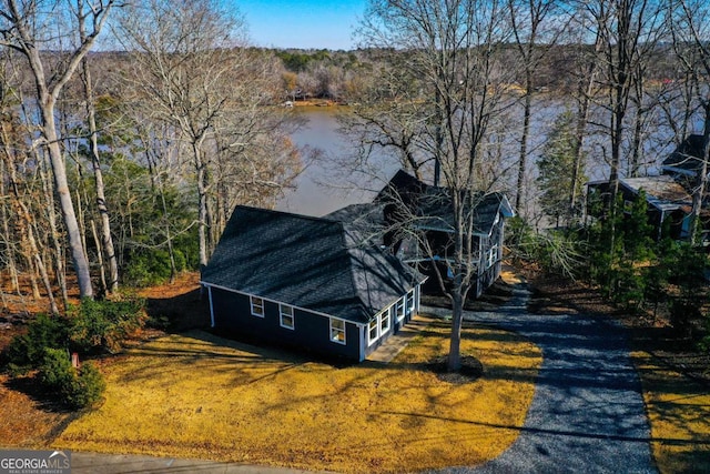 view of home's exterior featuring a sunroom, a water view, and a lawn