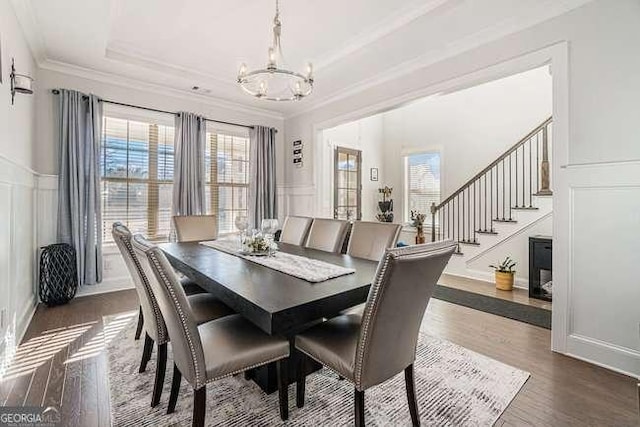 dining space featuring a raised ceiling, a chandelier, dark wood-type flooring, and ornamental molding