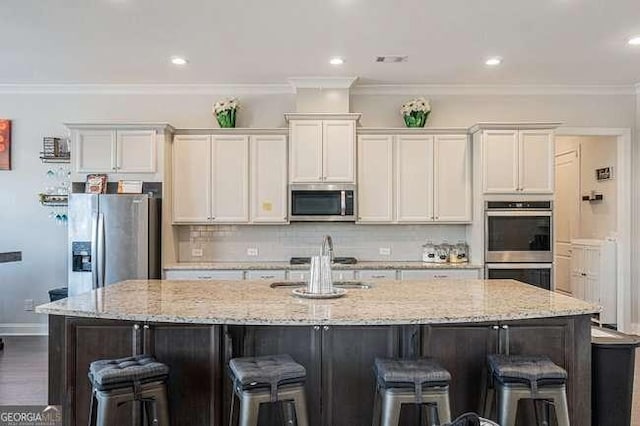 kitchen with a large island with sink, crown molding, white cabinets, and stainless steel appliances