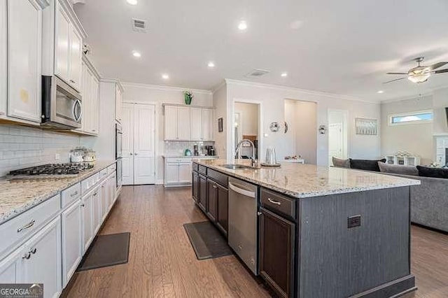 kitchen with white cabinetry, sink, stainless steel appliances, decorative backsplash, and a kitchen island with sink