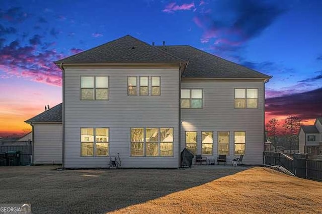 back house at dusk featuring a patio