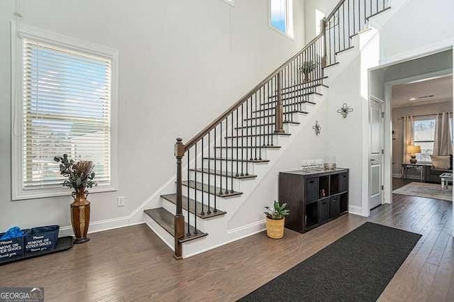 stairs featuring hardwood / wood-style floors and a high ceiling