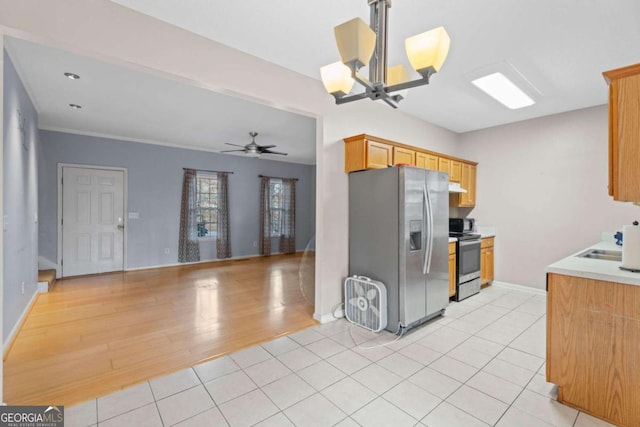 kitchen with sink, light hardwood / wood-style floors, ceiling fan with notable chandelier, and appliances with stainless steel finishes