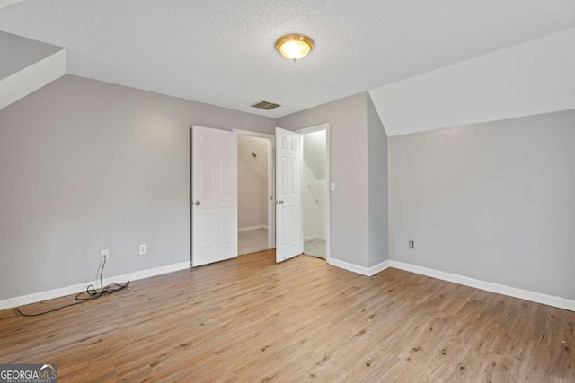 bonus room with a textured ceiling, light hardwood / wood-style flooring, and vaulted ceiling