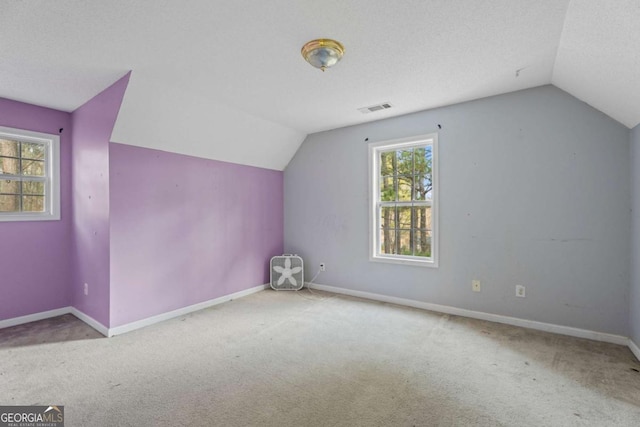 bonus room with a textured ceiling, light carpet, and vaulted ceiling