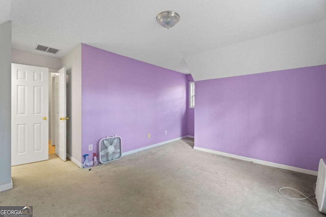 spare room with light colored carpet and vaulted ceiling