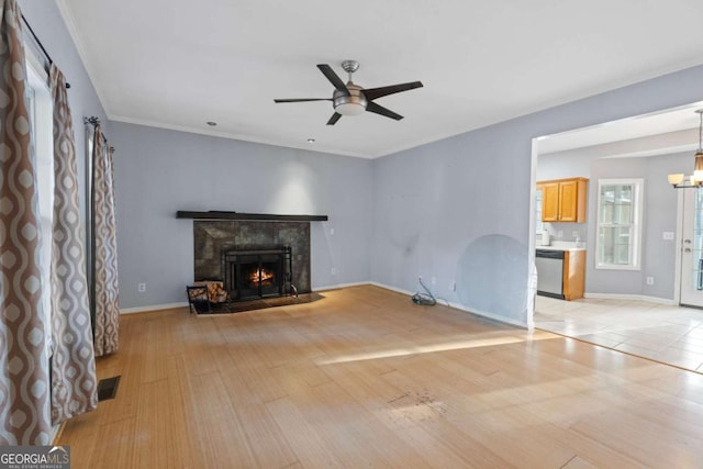 unfurnished living room with ceiling fan with notable chandelier and light hardwood / wood-style floors