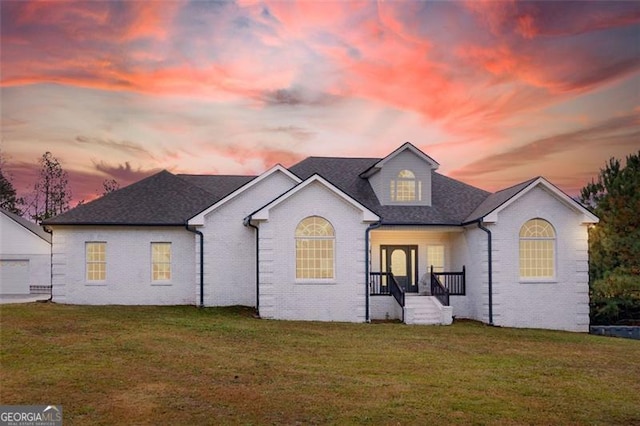 back house at dusk with a lawn and a garage