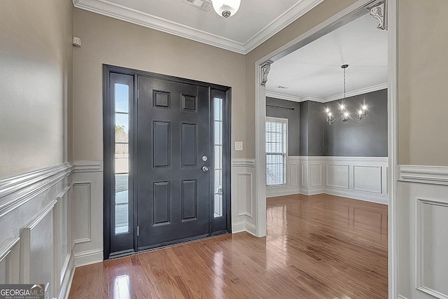 entryway featuring hardwood / wood-style floors, an inviting chandelier, and crown molding