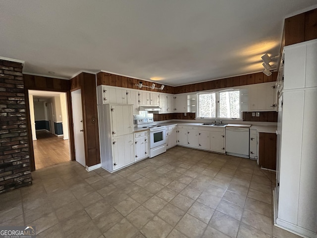 kitchen featuring wood walls, sink, white cabinets, and white appliances