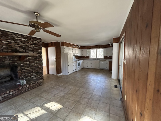 kitchen with ceiling fan, white appliances, wooden walls, a fireplace, and white cabinets