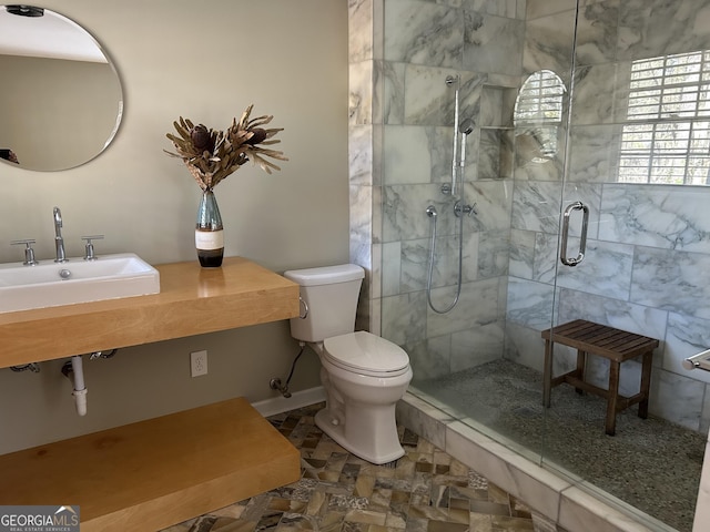 bathroom featuring sink, a shower with shower door, and toilet