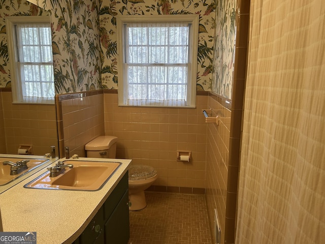 bathroom with tile patterned flooring, vanity, toilet, and tile walls